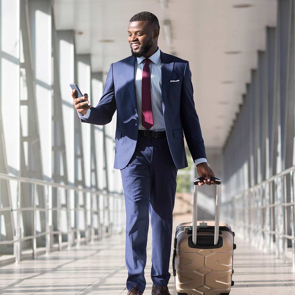 A young business man walks through an airport looking at his phone