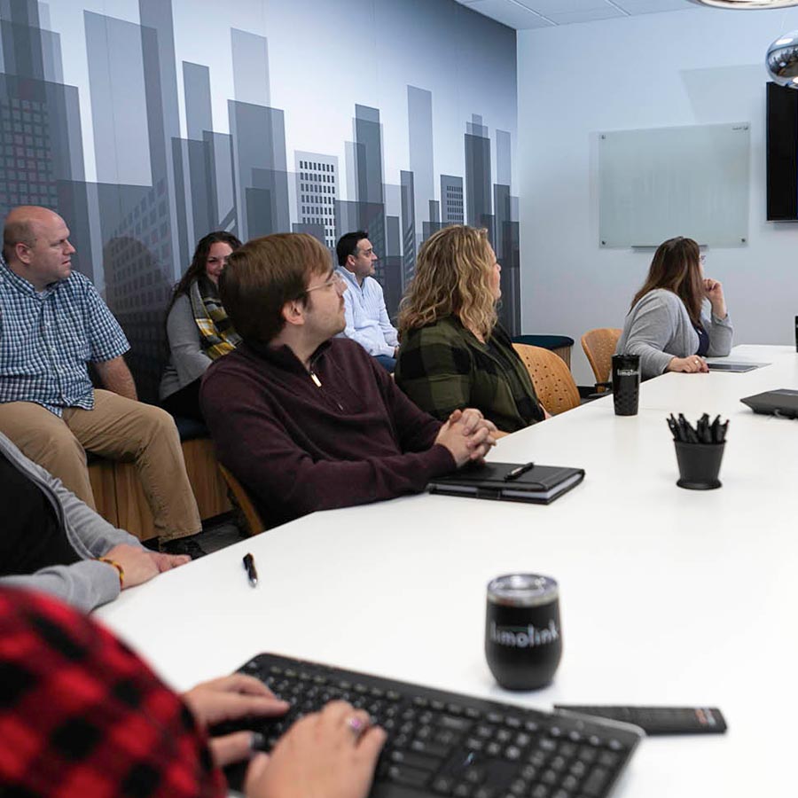 Several LimoLink employees sit around a table