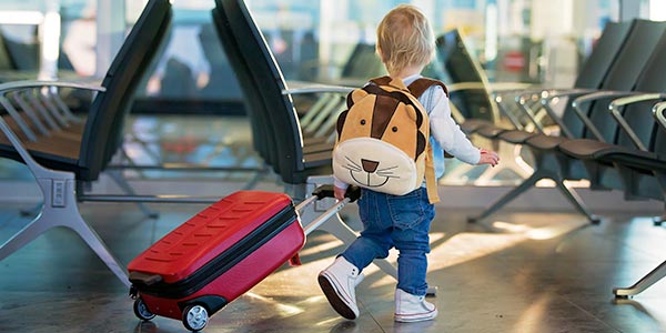 A child walks through an airport with a bag in tow