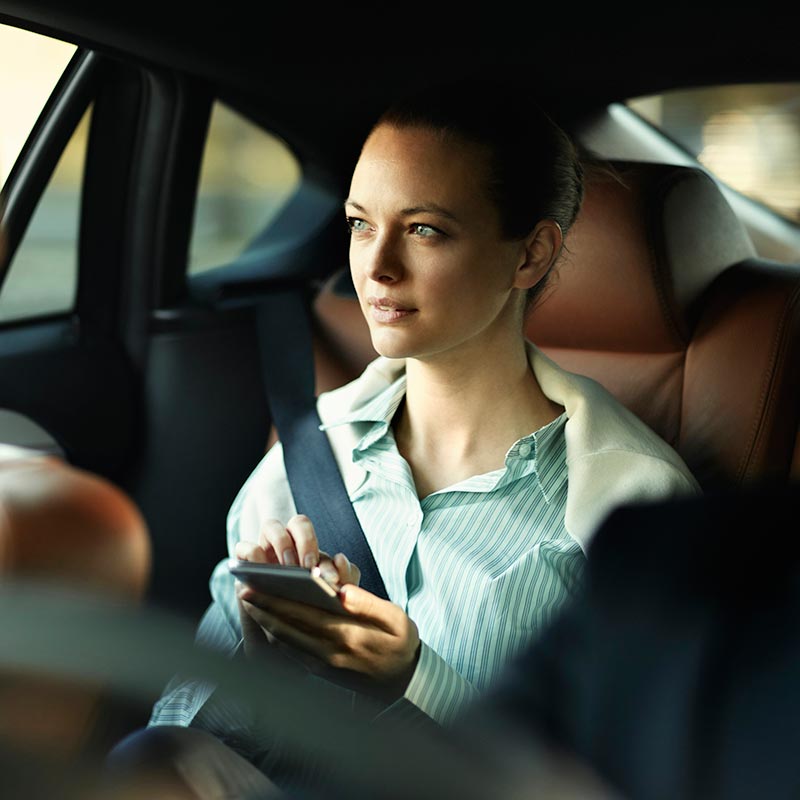 Woman in backseat of car using phone